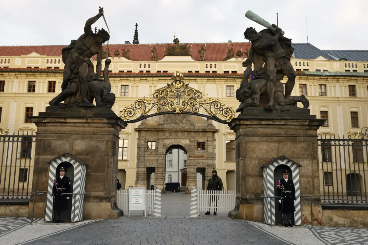 Hlavní vstupní brána na Pražský hrad s bojovníky na sloupech a strážci ve strážních budkách, symbolická pro hlídaný vstup do historického sídla českých králů