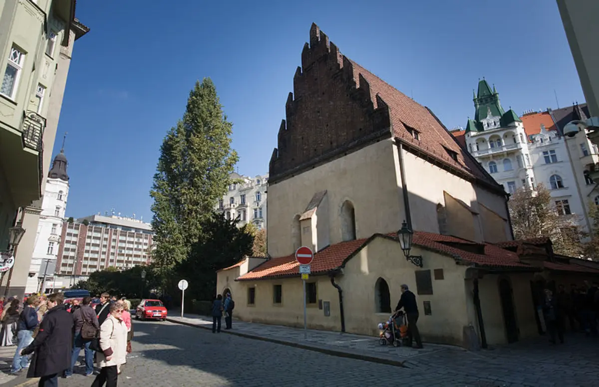 Návštěvníci a turisté stojí před Staronovou synagogou v Praze, obdivují historickou památku