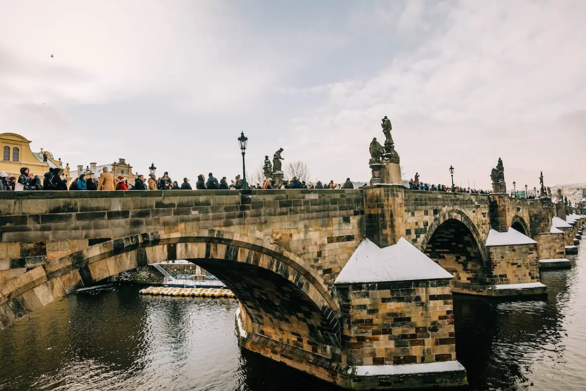 Visitors traverse snowy the Charles Bridge over Vltava River