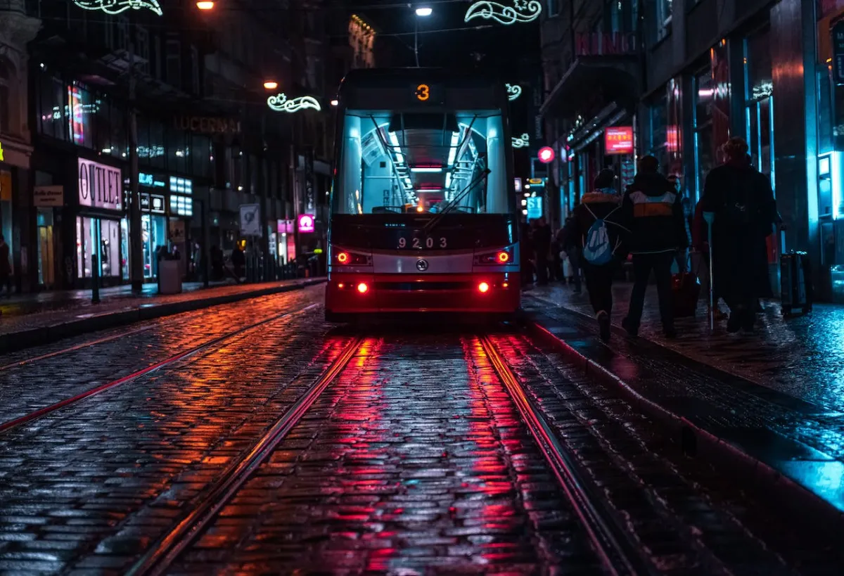 Night tram number 3 gliding through Prague streets with pedestrians on the sidewalk