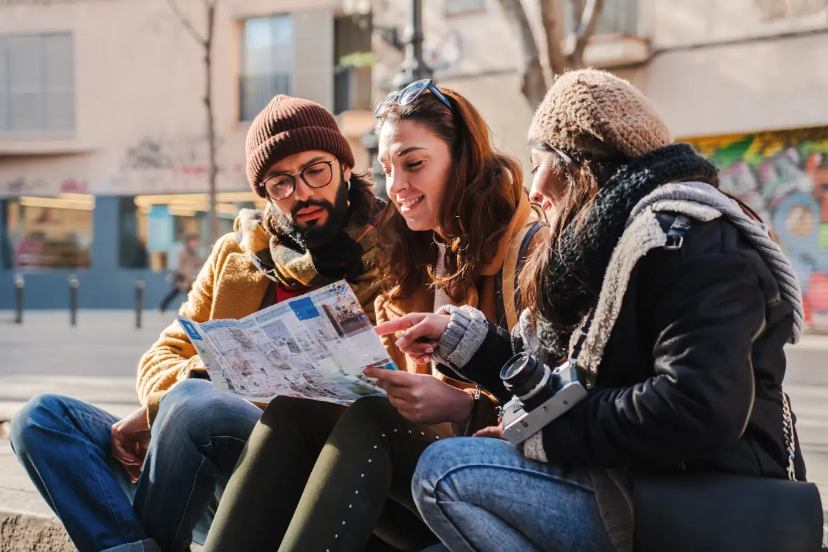 Young tourist friends consulting map on street